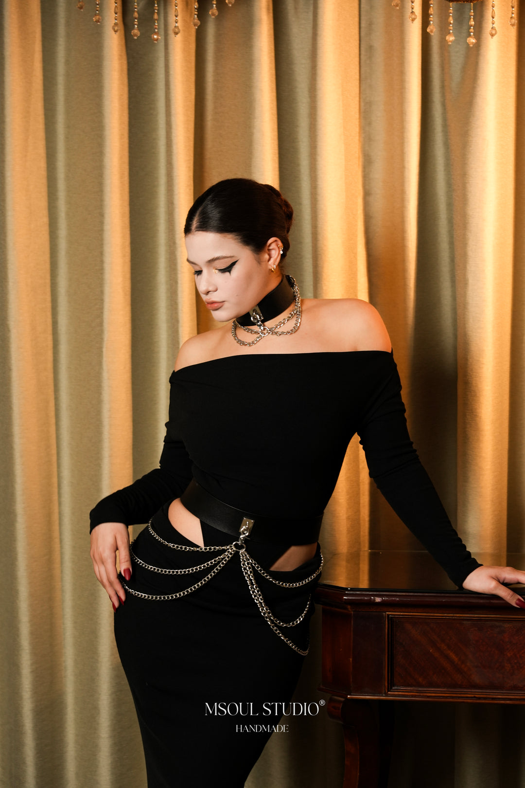 Model leaning on a table wearing the black leather chain belt