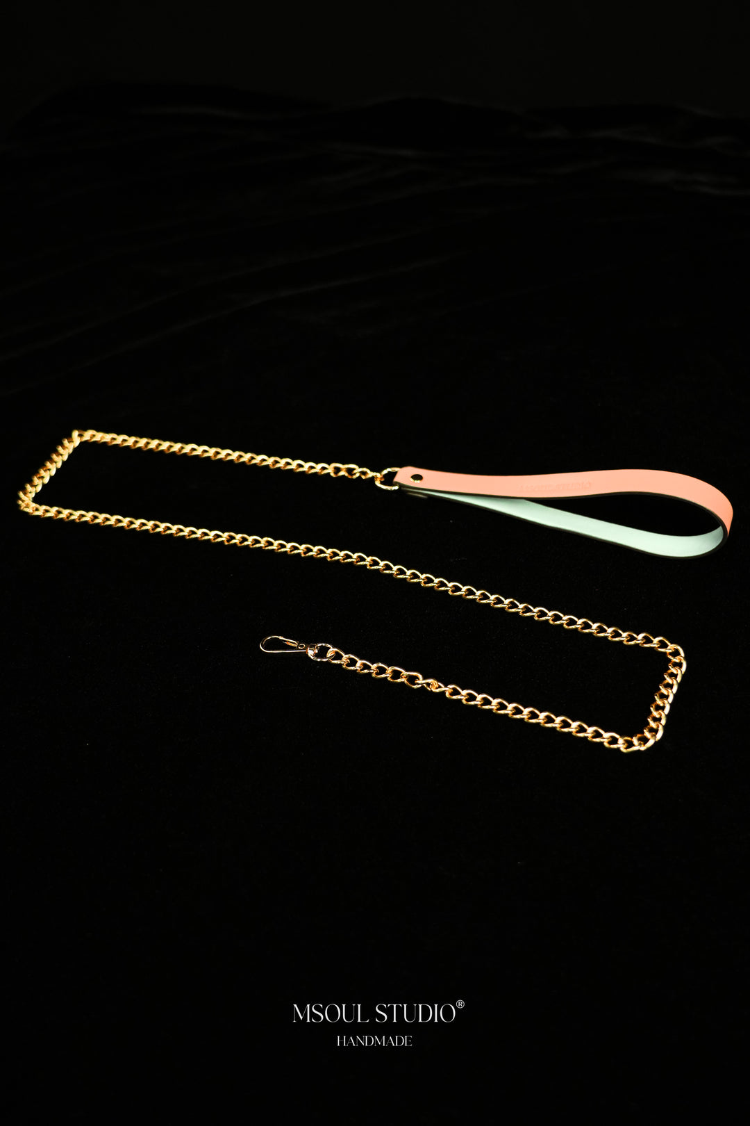 Pink handle with pale blue inner face joined to a gold-tone chain