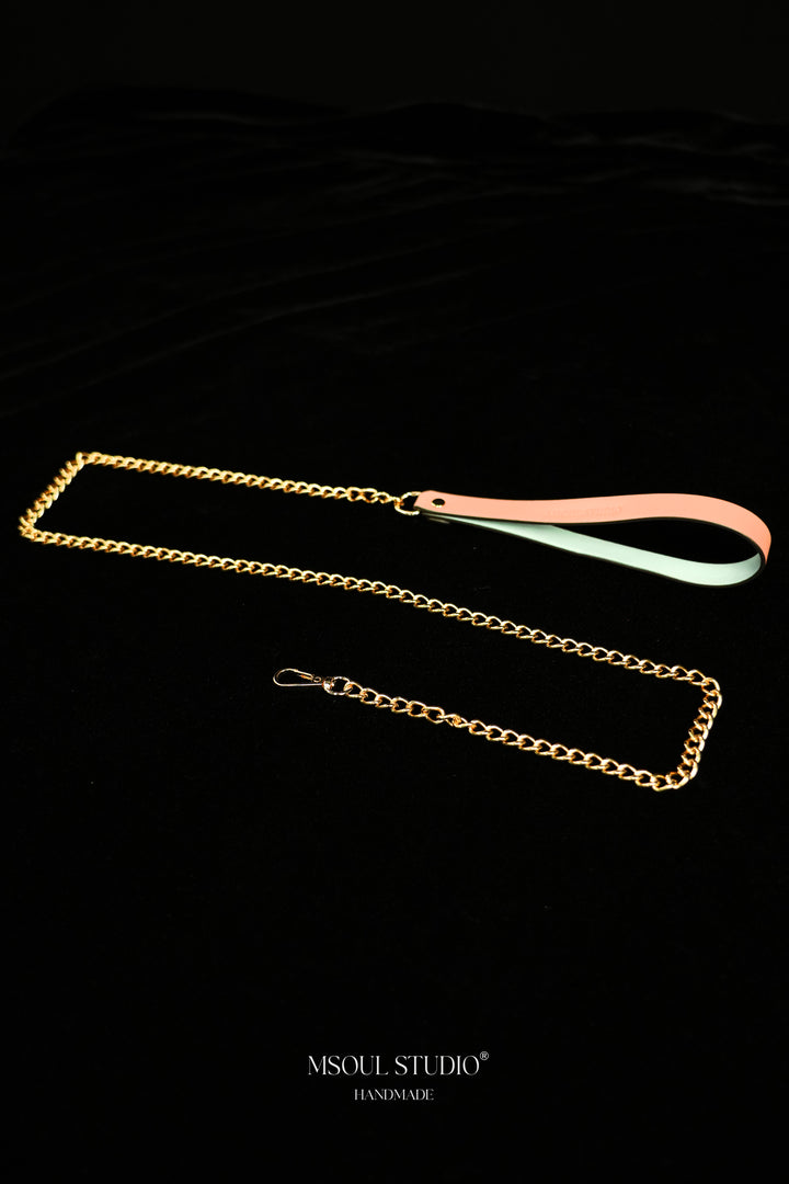 Pink handle with pale blue inner face joined to a gold-tone chain