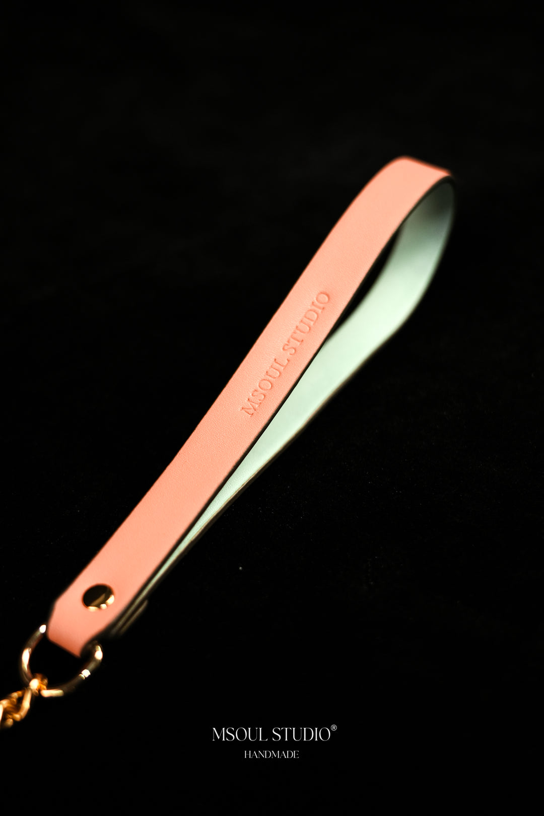 Close-up of the pink vegan leather handle with debossed logo and gold-tone ring