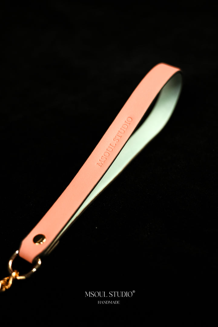 Close-up of the pink vegan leather handle with debossed logo and gold-tone ring
